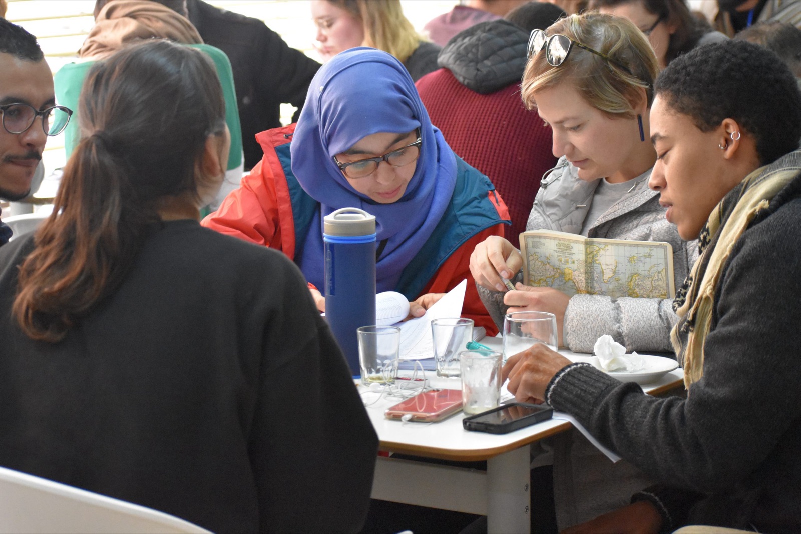Students and Moroccan speakers lean over a table at the Arabic Language Café, sharing notes and a small map
