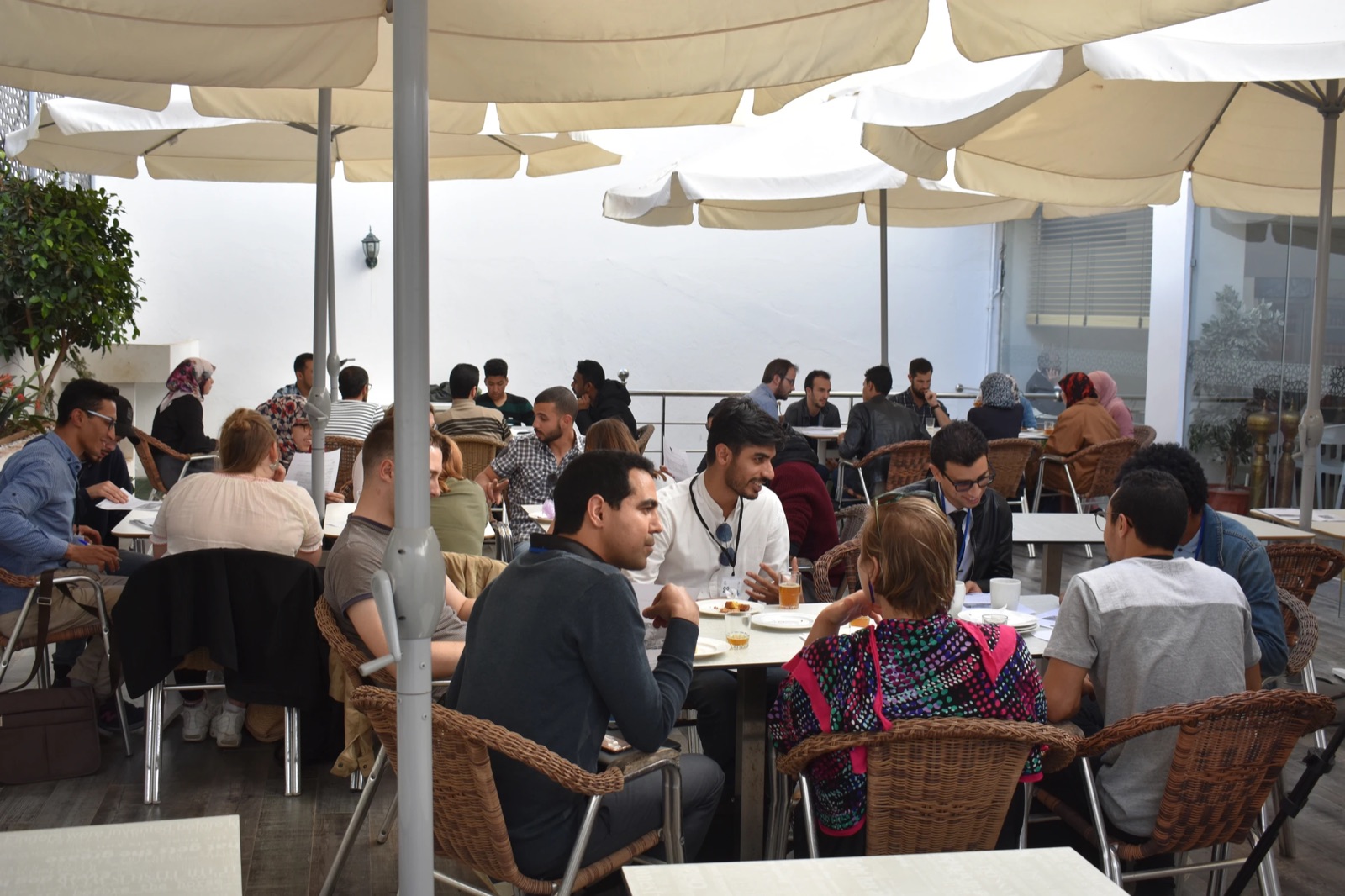 The center's terrace under white parasols, full of students talking at small tables